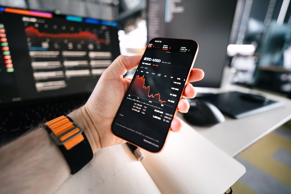 A person looks at a cryptocurrency price chart on a phone, waiting to see whether the crypto market will go back up
